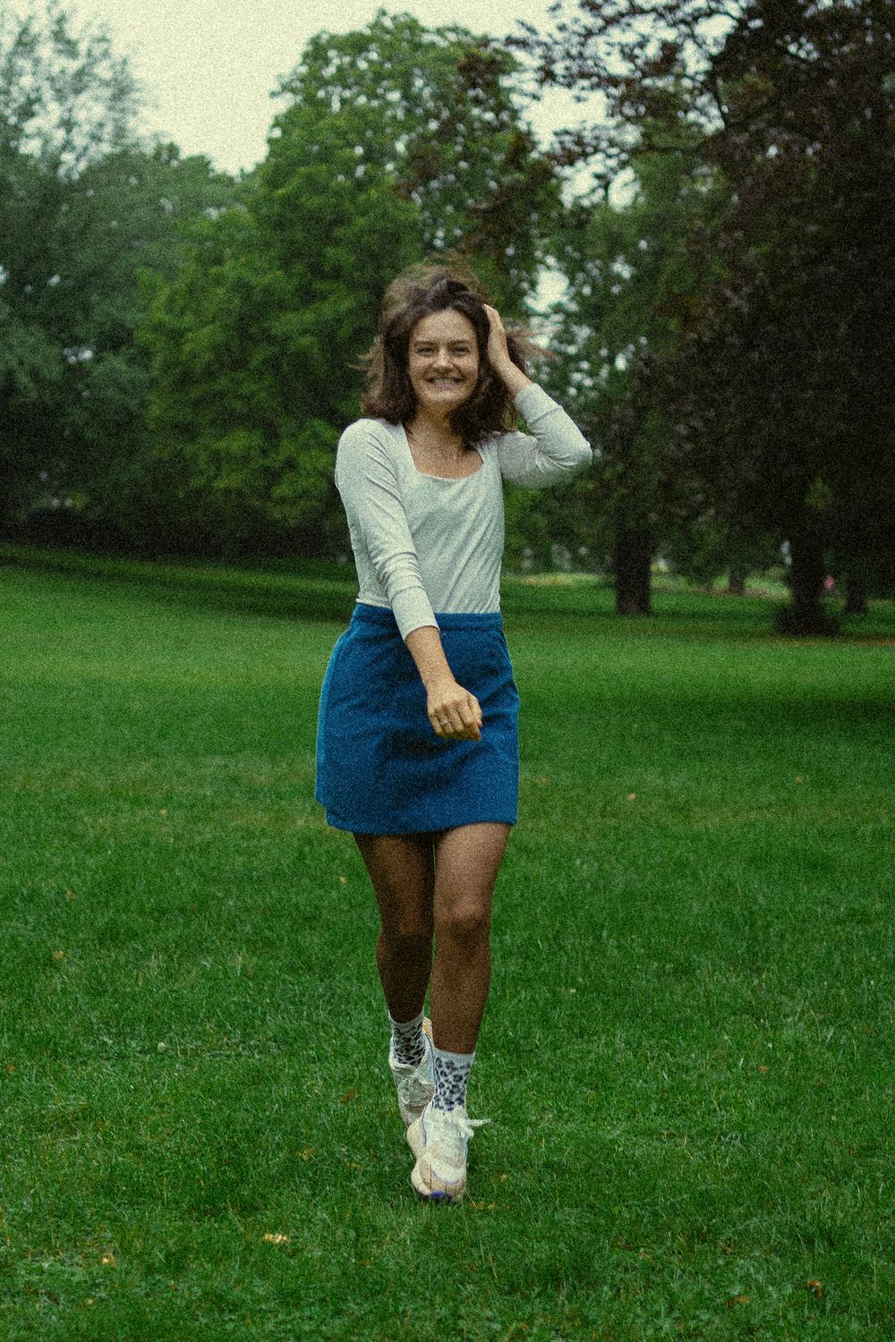 Frau fässt sich durch Haar und lächelt - Portrait Fotoshooting im Grünen im Blüherpark Dresden
