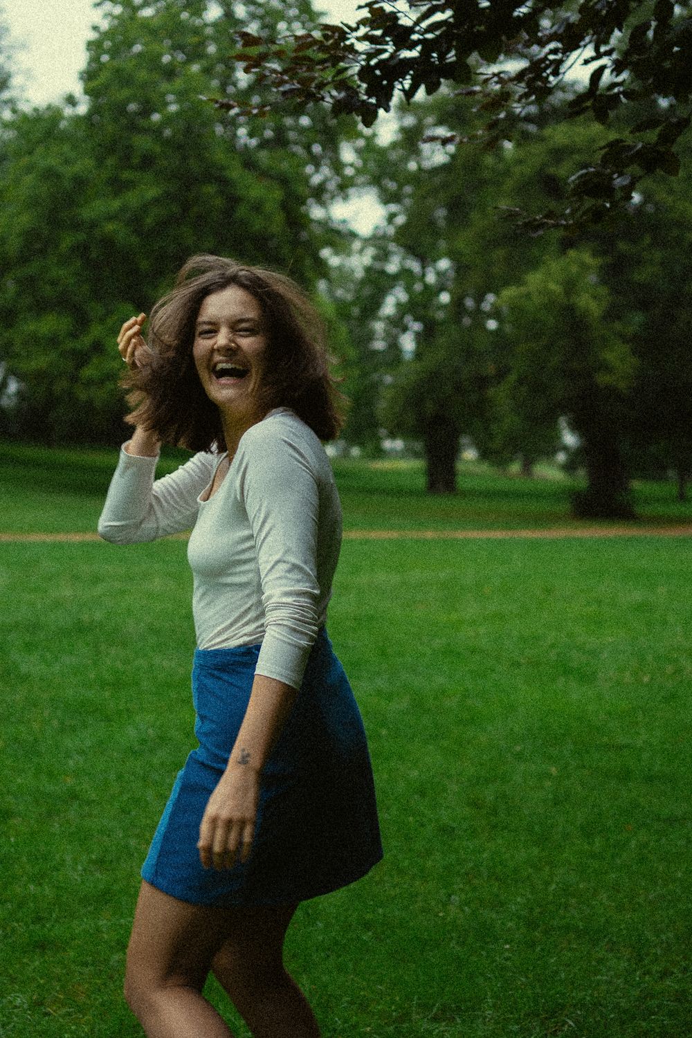 Portrait Fotografie einer herzhaft lachenden Frau  während sie durch den grünen Park läuft im Blüherpark Dresden