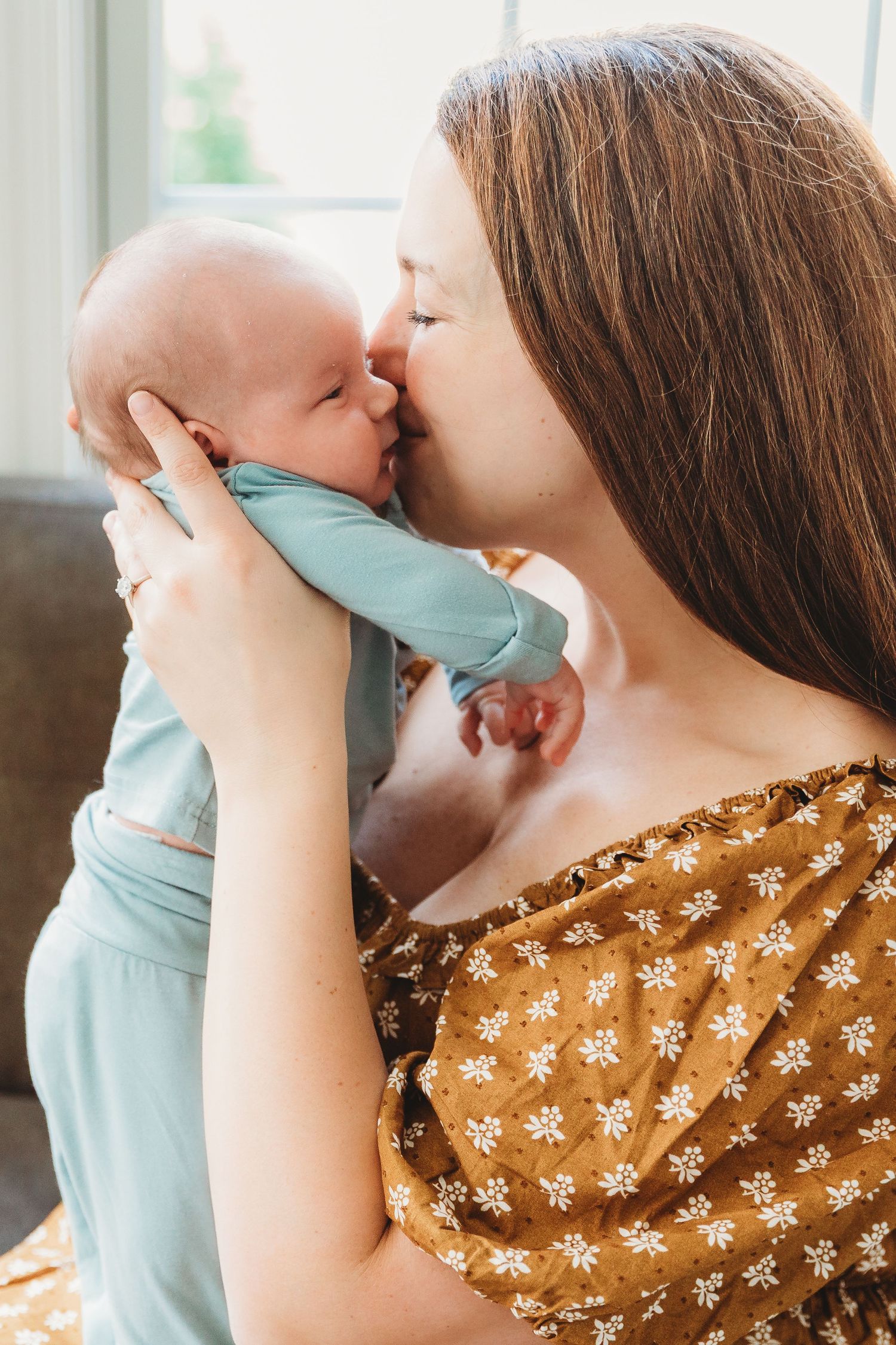 Tender parenting moments captured in soft natural light through window.