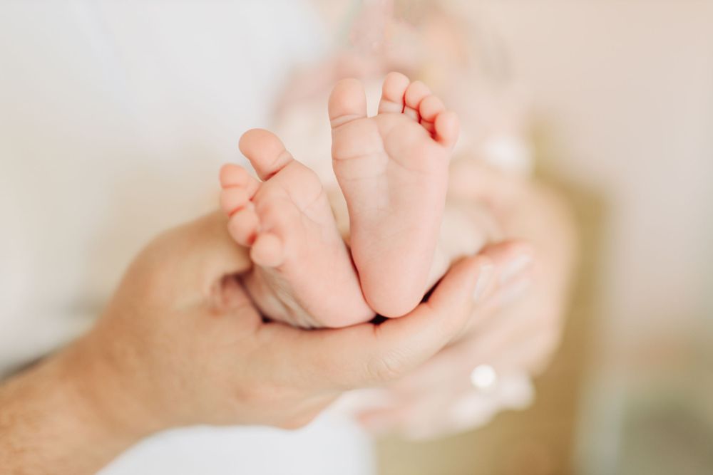 Tiny baby feet in dad's hands.