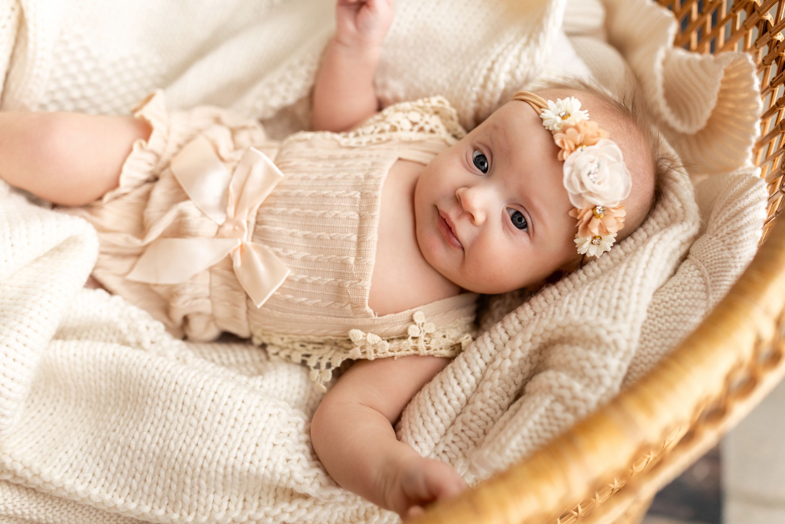 A collage of baby photos showing an infant in cream knit clothing lying in a woven basket against a neutral background.