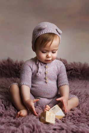 Small child in knit sweater sitting on purple rug playing with wooden blocks in progression of photos.