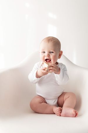 Four sequential photos of a baby in white onesie sitting against white background showing different playful poses.