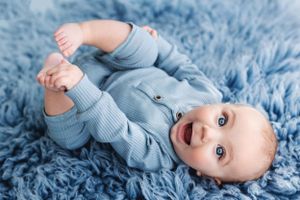 Infant in light blue outfit lying on soft blue blanket.