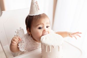 Joyful moment of cake tasting during first birthday celebration.