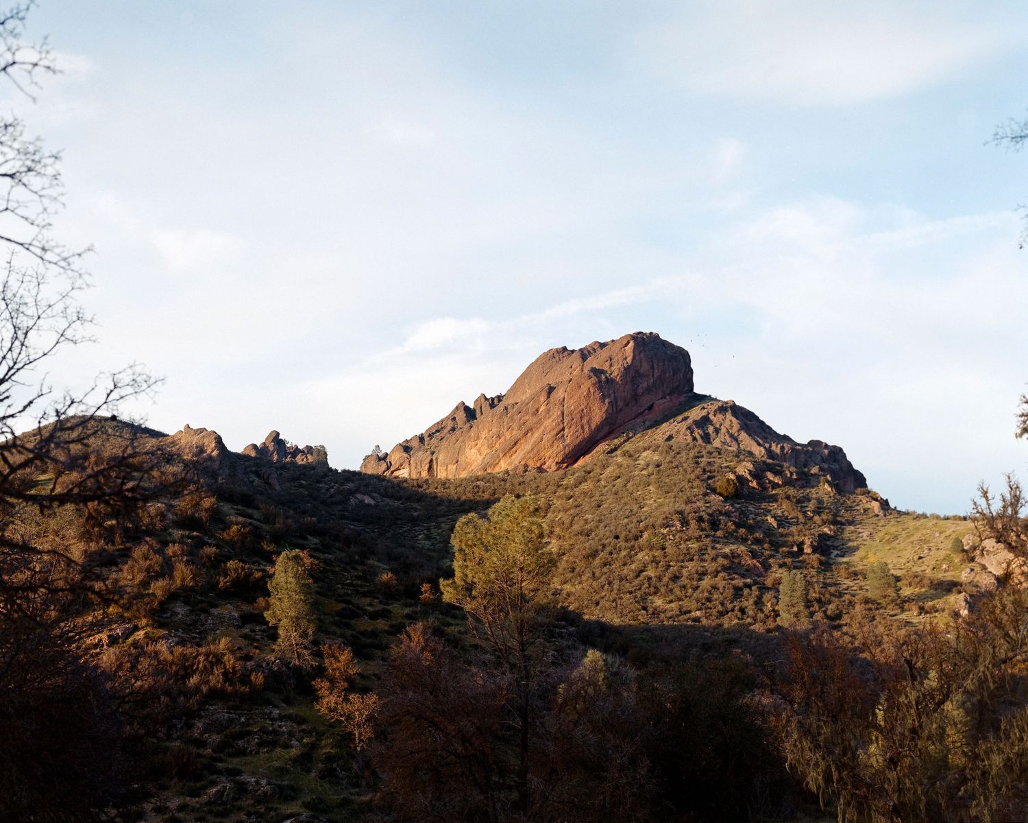 A rugged mountain peak rises against a blue sky during golden hour.