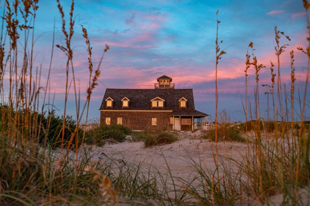 Lifesaving station Pea Island, North Carolina Outer Banks at sun set with pink and purple clouds and dune grass.