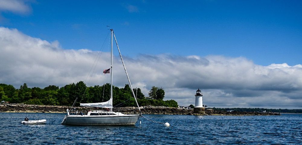 Sailboat moored in harbor with Derby Light Station in background, Salem Harbor, Salem, Massachusetts.