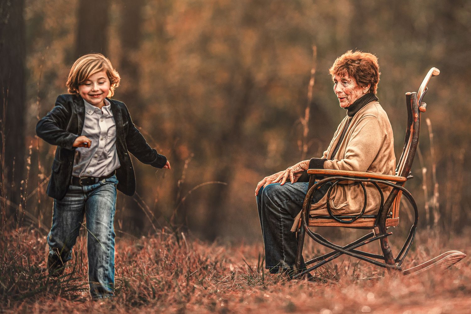 Two people enjoying an autumn day outdoors, one sitting in wooden rocking chair while the other stands in a field.
