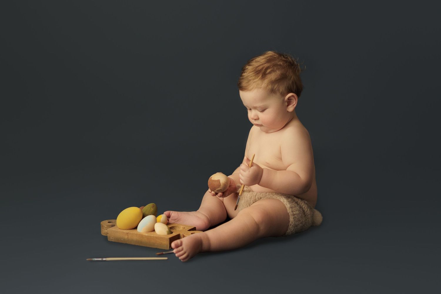 Multiple connected images showing infant posing with citrus fruits in professional dark studio setting.