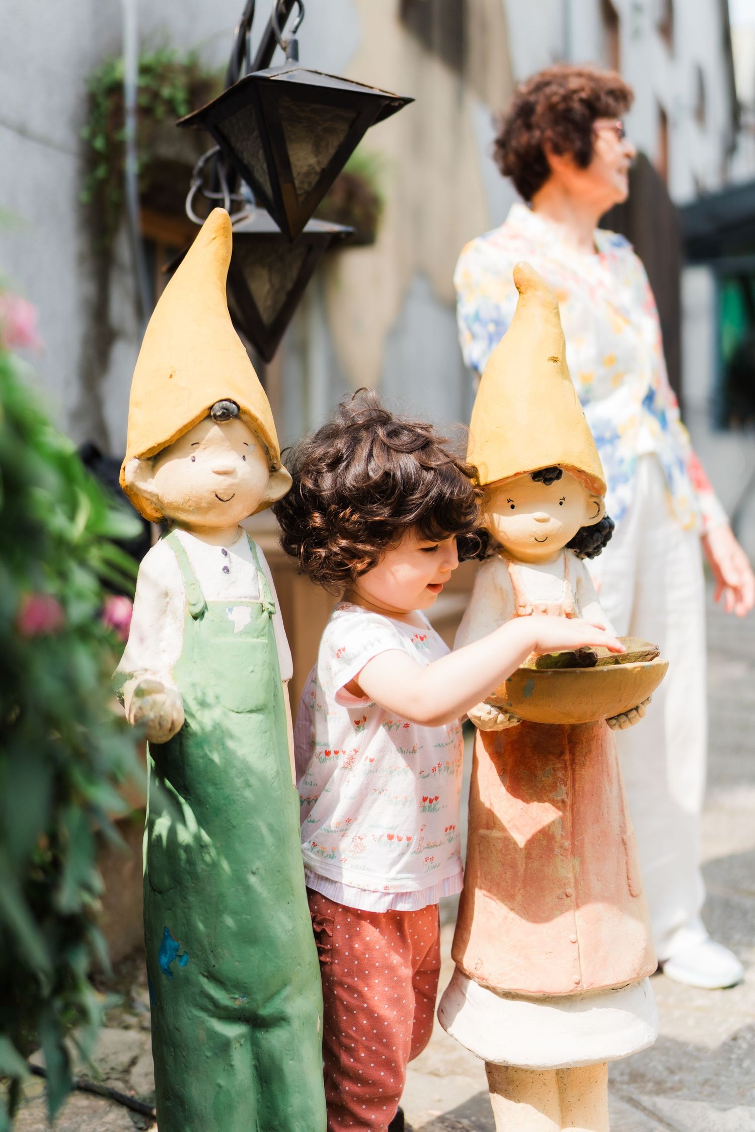 Decorative garden gnome statues in pastel colors line a street.