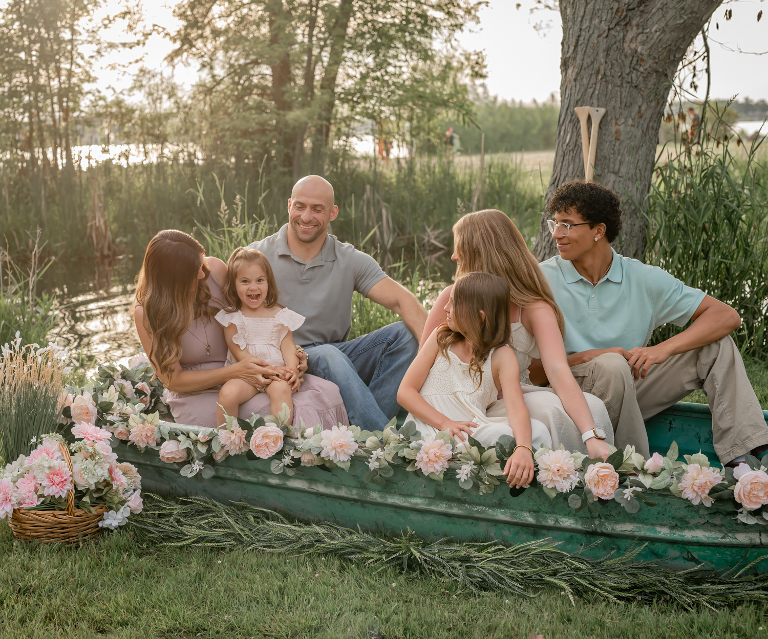 A multi-generational family poses together on a wooden bridge surrounded by lush greenery.