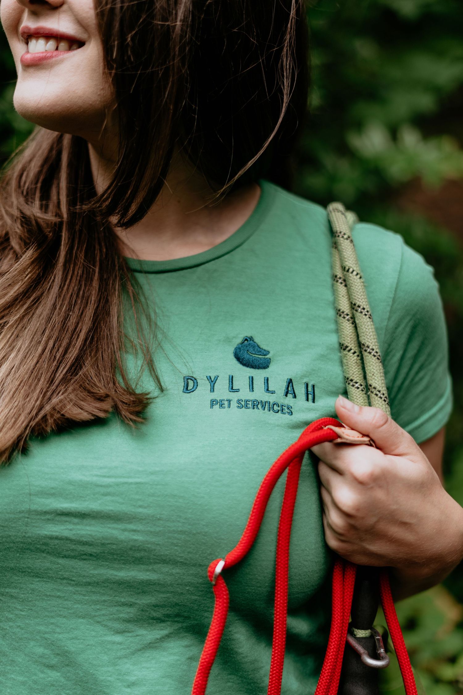 Close-up of mint green pet services t-shirt with red leash detail.