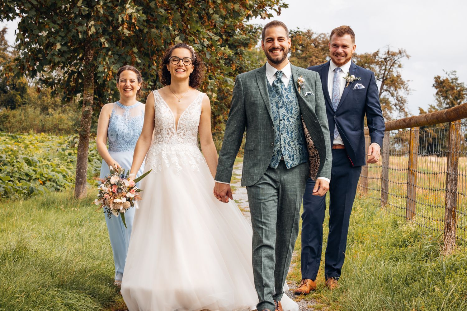 Wedding party walking down a grassy aisle during an outdoor spring ceremony.