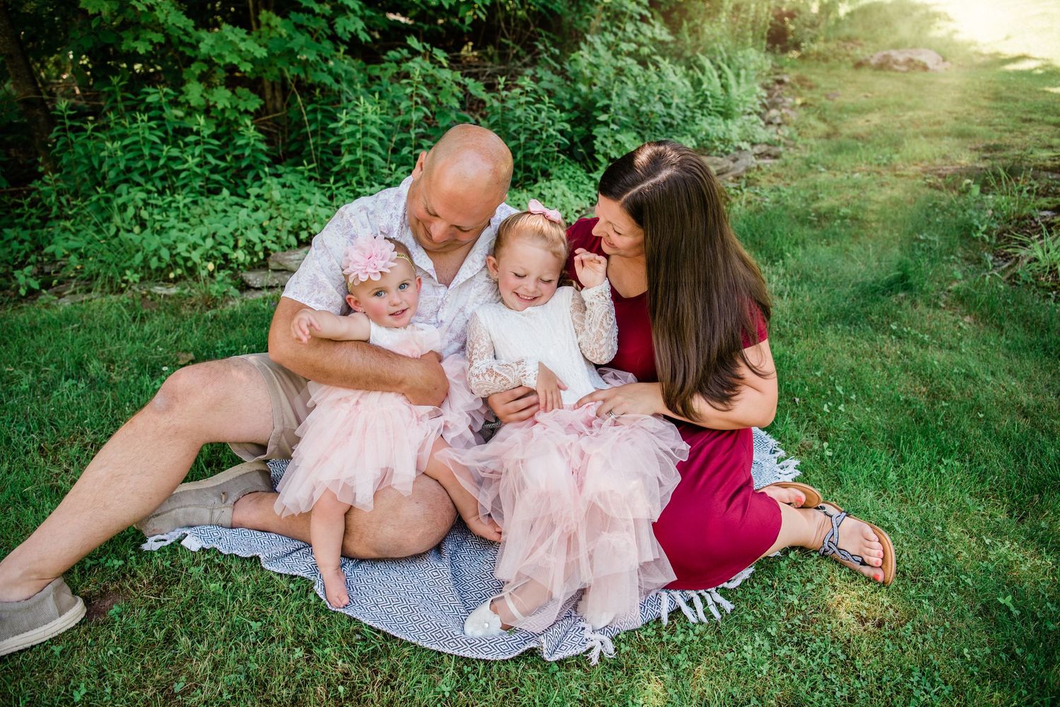 Family photoshoot in a lush green garden setting during golden hour.