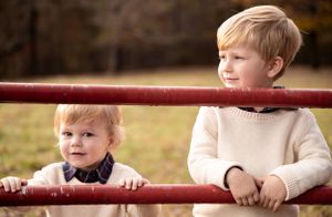 Child playing on red metal equipment during autumn family photo session.