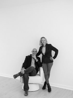 Four black and white artistic photographs show a person posing with a white sculptural chair against a plain wall.