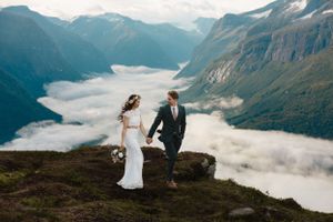 A couple enjoys a breathtaking mountain vista with fog-filled valleys below during their wedding.