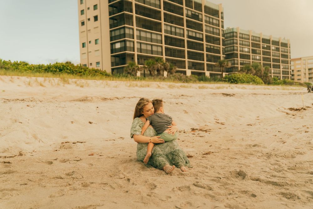A gentle scene on a sandy beach with beachfront condominiums in the background during golden hour.