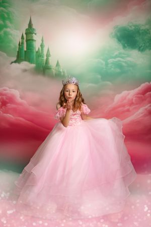 A magical fairy tale scene with a pink gown against dreamy pink clouds and a distant castle in a mint green sky.
