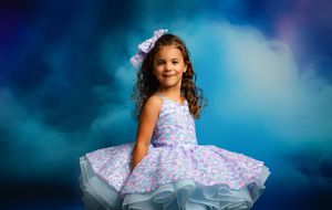 A dancer in a flowing white and purple dress gracefully twirls against a dreamy blue background.