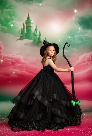 Fantasy portrait of a witch in a flowing black ball gown and hat holding a staff against a magical castle backdrop.