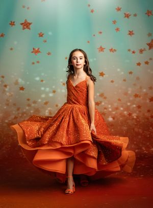 Whimsical portrait with orange glitter dress against teal background with floating stars and magical lighting effects.