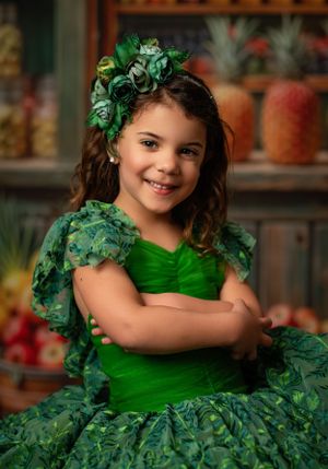 Whimsical portrait in emerald green dress with matching floral headpiece.