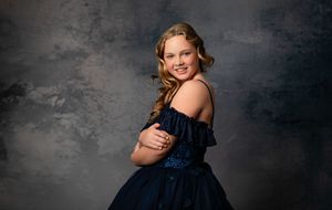 A collection of six studio portraits showing a young girl in a navy blue dress against a dark gray backdrop.