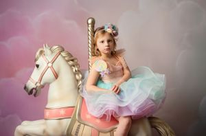 Whimsical photo with vintage carousel horse and pastel tulle dress against dreamy background.