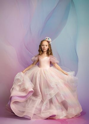 Dreamy portrait of child in layered pink tulle gown against purple and blue watercolor background.