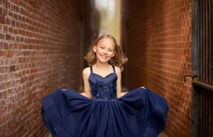 Portrait in an urban brick alley featuring a navy blue formal dress.