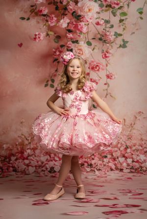 Pink tulle party dress with floral details photographed against a romantic rose petal backdrop.