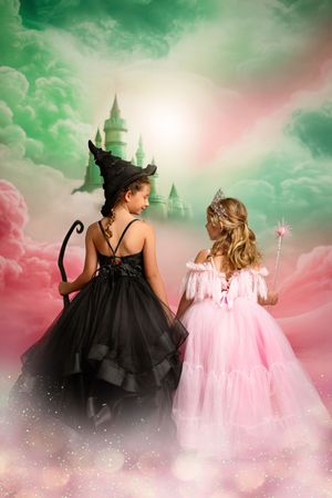 Two figures in contrasting black and pink gowns pose against a dreamy green and pink clouded fantasy backdrop.