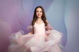 Pink tulle dress portrait against soft pastel background.