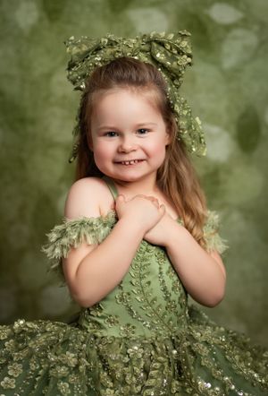 A whimsical portrait featuring a green fairy-like dress adorned with delicate foliage and a matching leafy crown.