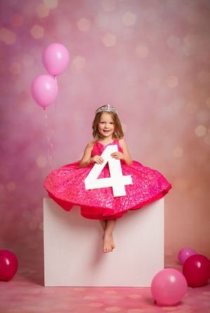 Festive pink birthday setup with decorative number 4, balloons, and sparkly backdrop with bokeh lighting effects.