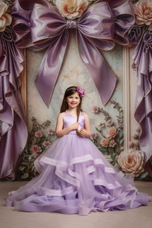 Lavender princess gown with flowing ruffles amid purple bows and peach roses in an elegant portrait backdrop.