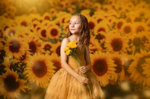 Dreamy summer portrait in a sunflower field with golden light and bokeh effects.