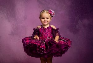 A small child in a purple tutu dress poses against a plum-colored backdrop in a series of photoshoot portraits.