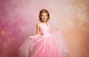 Young girl in pink princess ball gown posing with bokeh background.