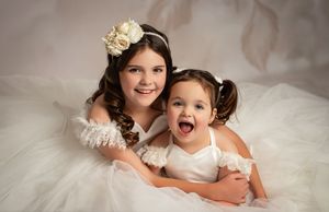 A series of soft sepia-toned studio portraits showing tender moments between parent and child on white fabric.