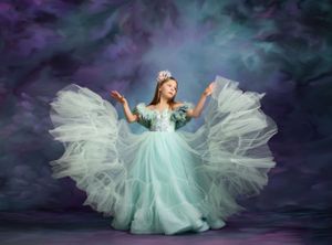 Magical fantasy portrait with a flowing teal gown against a dramatic purple sky.