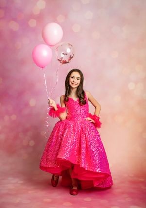 Festive photo with sparkly pink dress and pink balloons against soft bokeh background.
