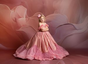 Dreamy portrait featuring a flowing pink ballgown against a soft rose-colored background.