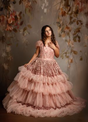Elegant pink layered tulle gown with delicate lace details photographed against an autumn-themed backdrop.