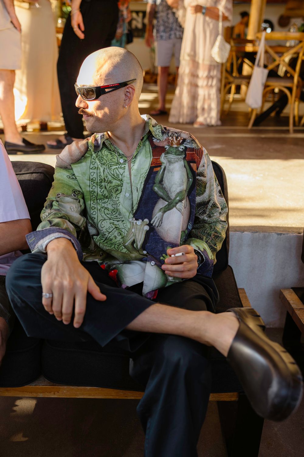 Someone wearing a green patterned shirt sits casually at a bar or restaurant holding a beverage. Hvar, Croatia