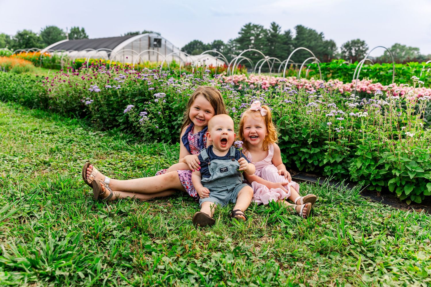 Happy moment captured in flowering garden with greenhouse in background.