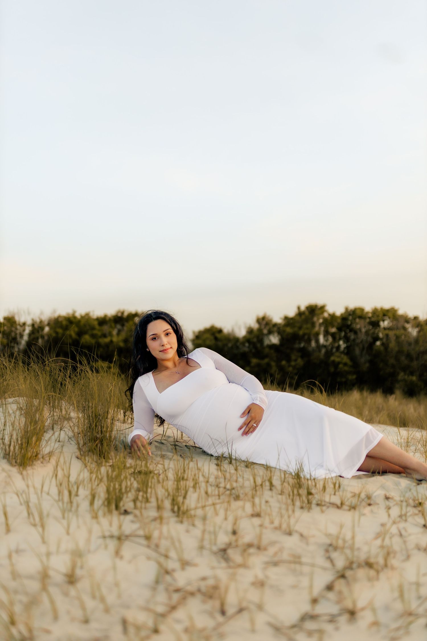 Dreamy sunset maternity photos in field of wild sunflowers with white top and jeans.