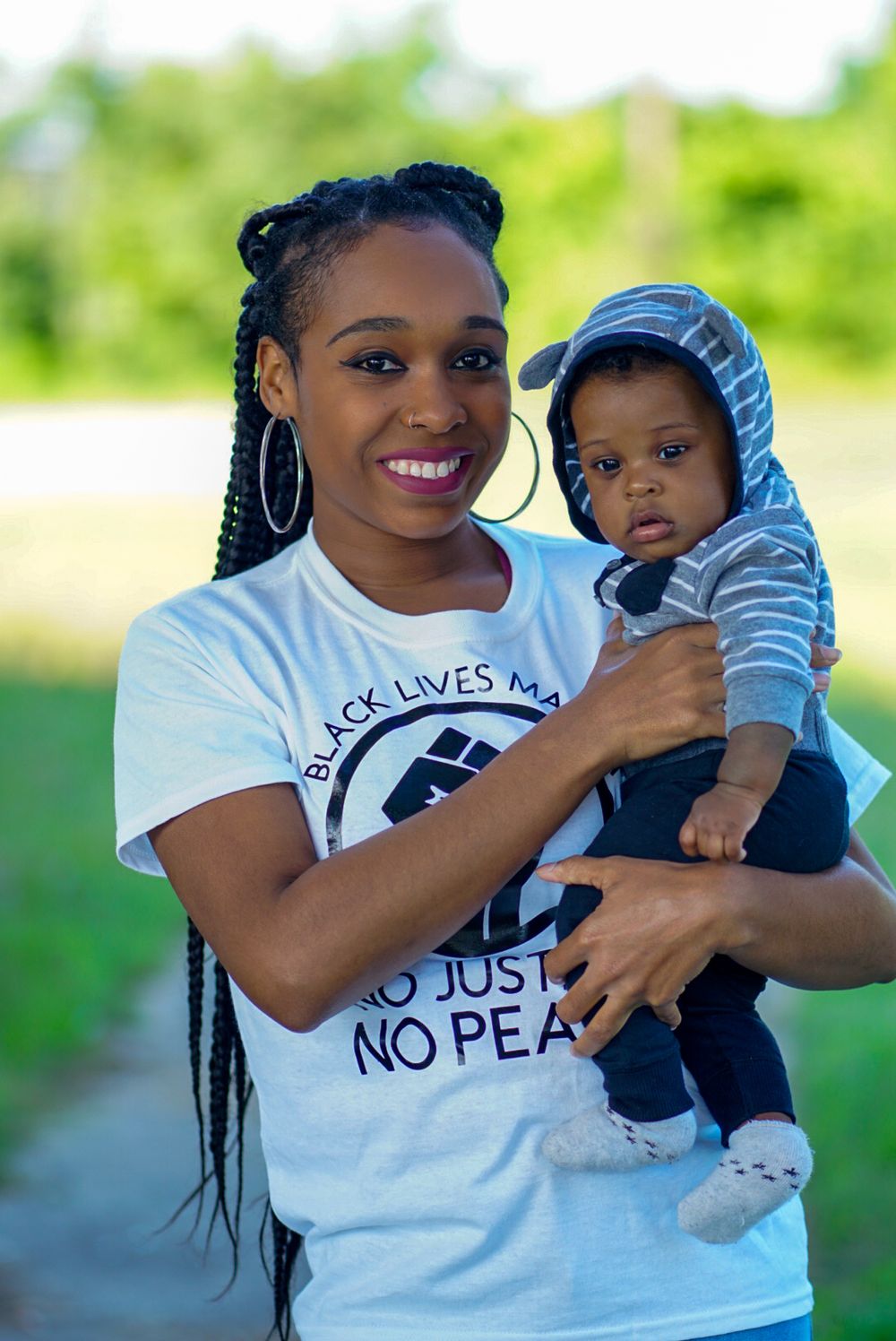 Mother and baby sharing a tender moment outdoors in casual attire.